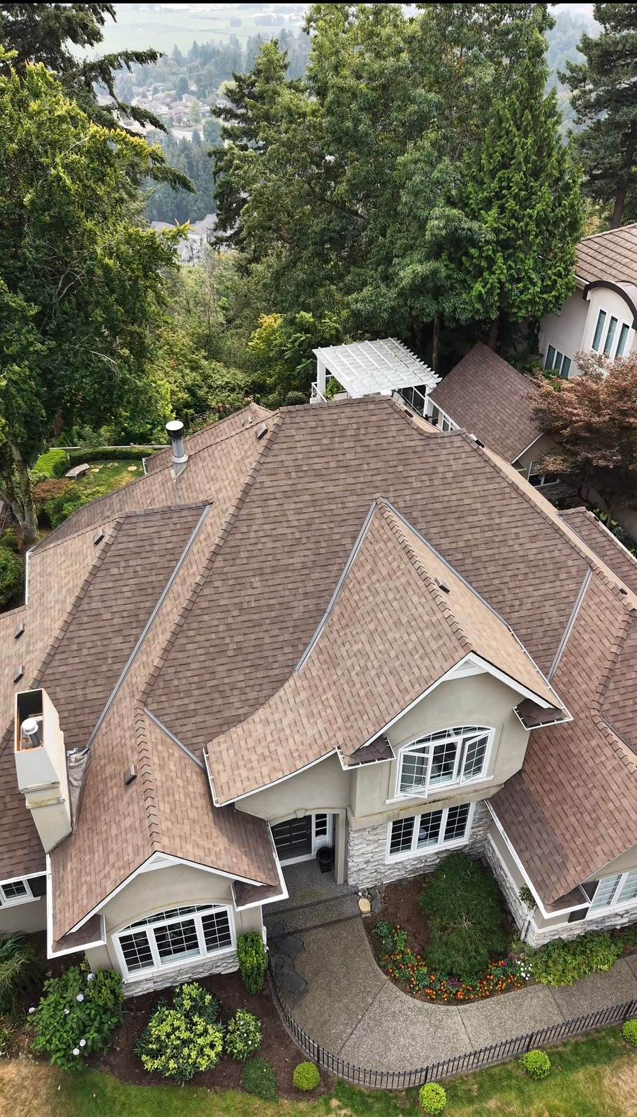 Completed architectural asphalt shingle roof on a large home on Eagle Mountain, with the Fraser Valley visible through conifers behind