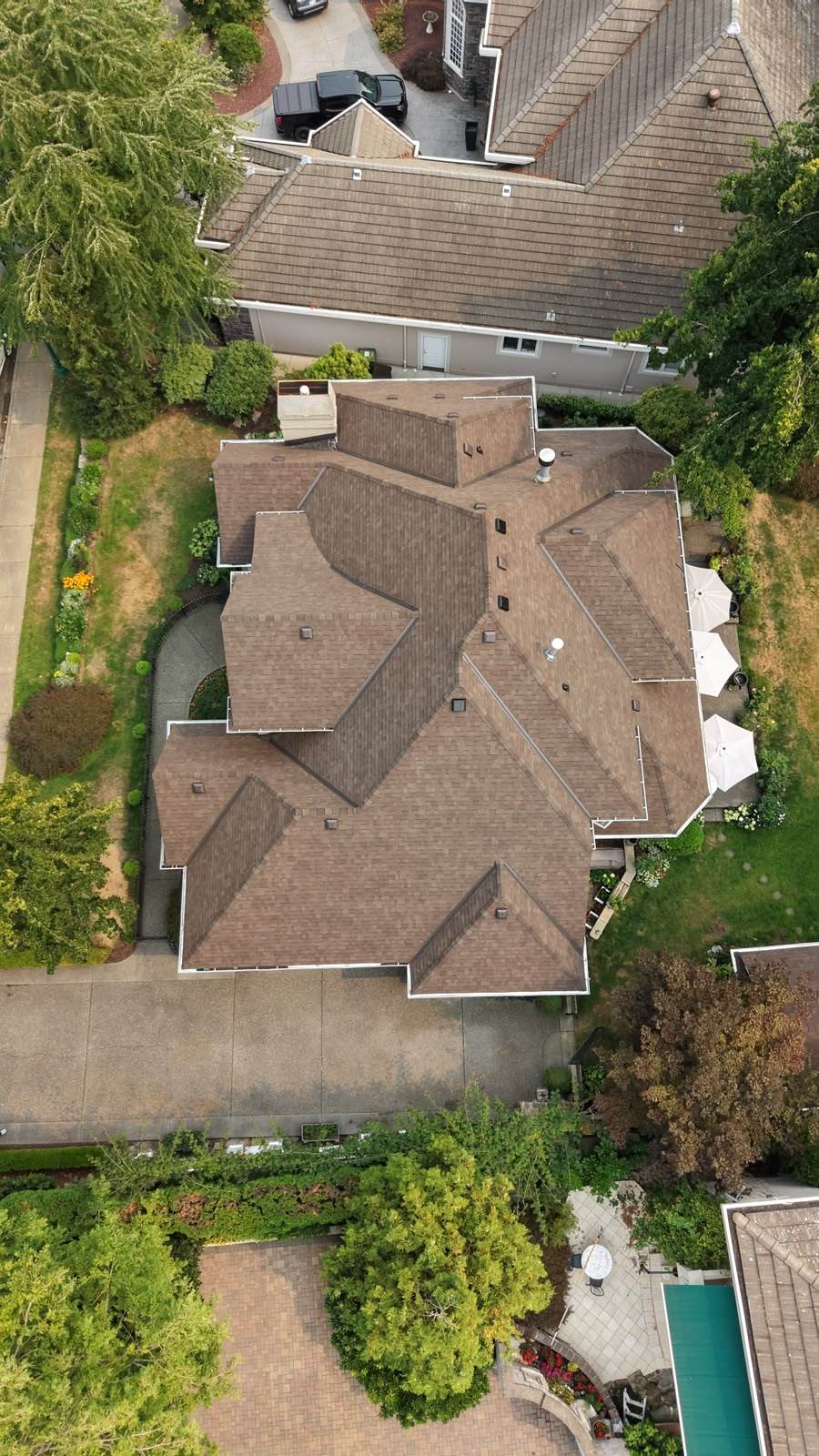 Overhead view of a completed architectural asphalt shingle roof on a large hillside home