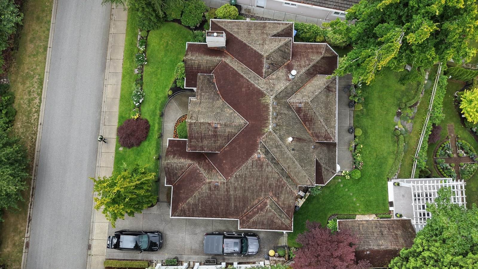 Overhead view of an aged cedar shake roof darkened by moss and organic staining, with wear concentrated in the valleys